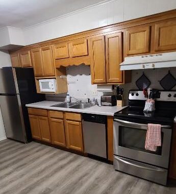 an empty kitchen with stainless steel appliances and wood cabinets