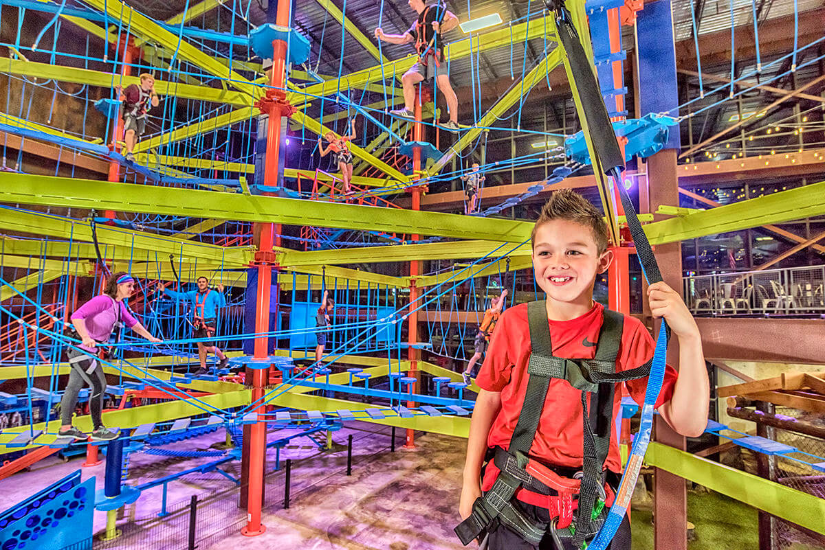 a young boy smiles as he stands in front of an obstacle course