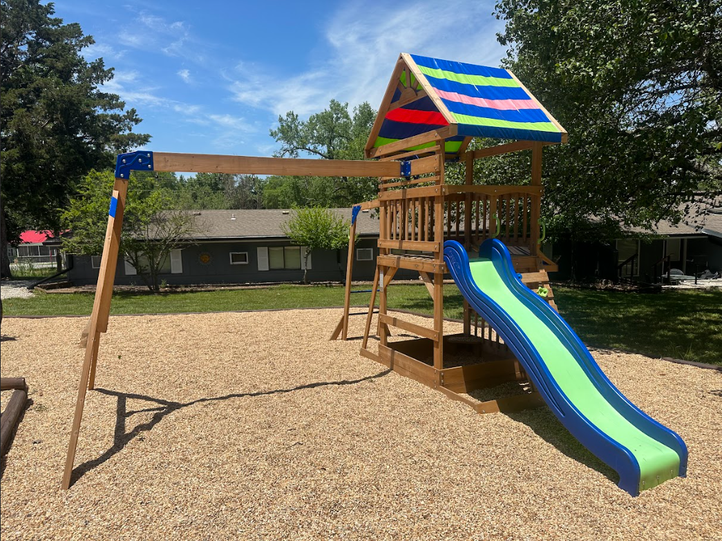 a wooden swing set with a colorful slide