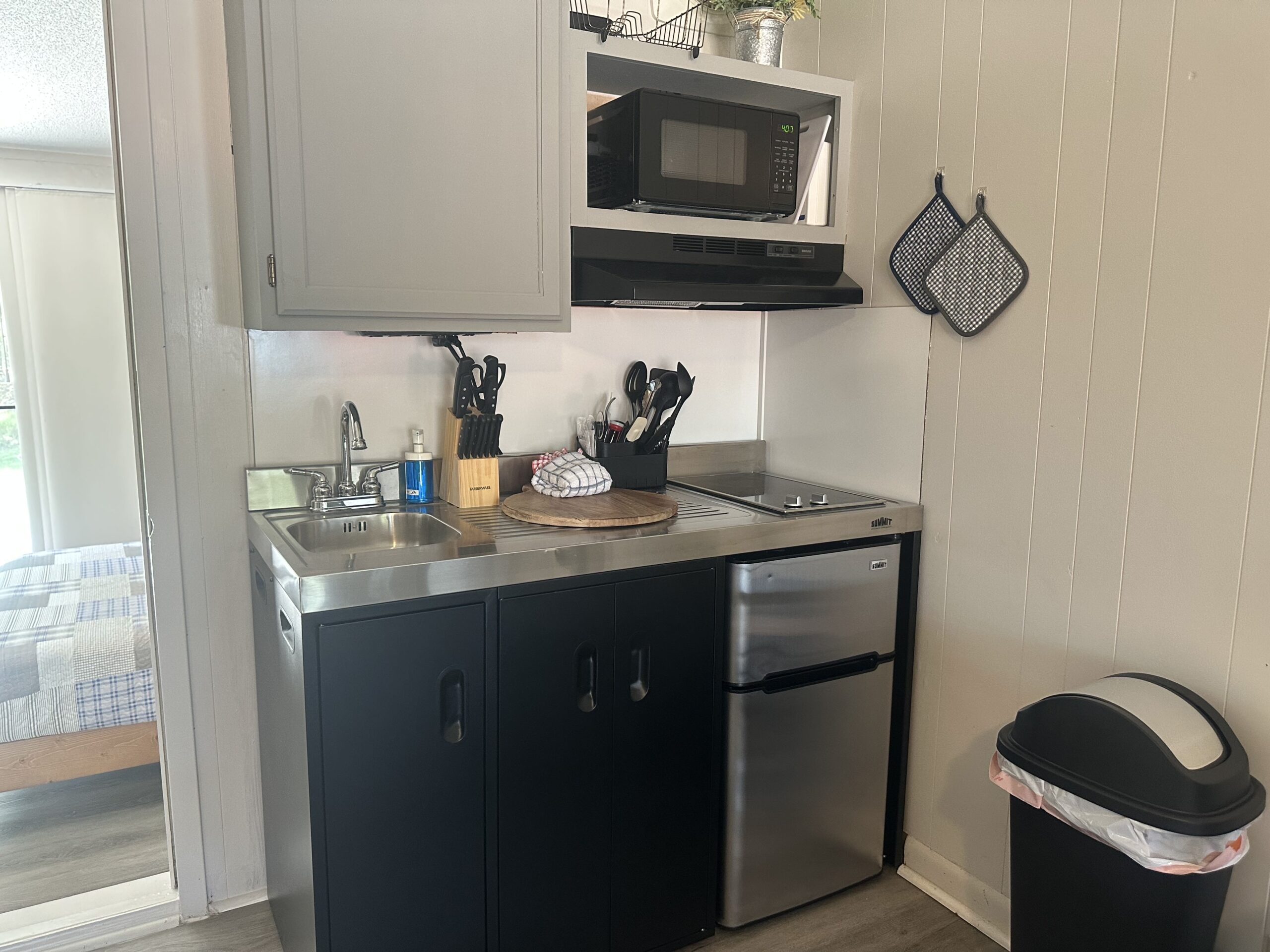 a small kitchen with stainless steel appliances and black cabinets