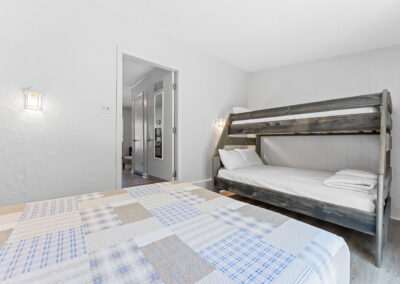 a bedroom with two bunk beds and a door leading to another room