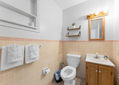a bathroom with a toilet, sink, and mirror