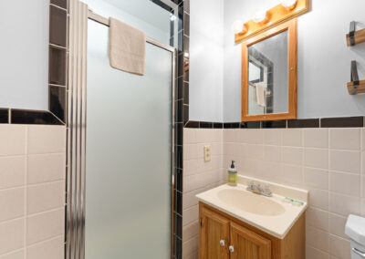 a bathroom with a sink, mirror, toilet and shower stall