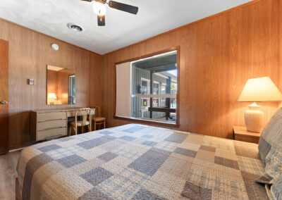 a bed room with a neatly made bed and a ceiling fan