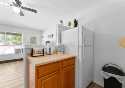 a kitchen with a refrigerator, microwave, and a trash can