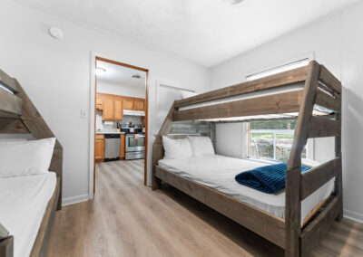 a bedroom with bunk beds and a kitchen in the background