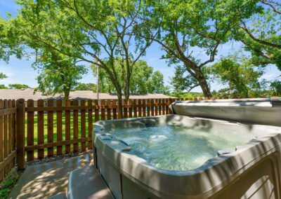 a hot tub sitting on top of a patio next to a wooden fence